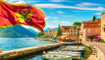 Flag and historic town of Perast at Bay of Kotor in summer, Montenegro