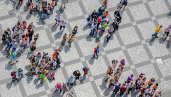 Different groups of people gather together on a paved, gridded square.